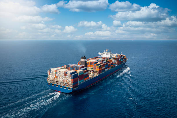 A large container cargo ship travels over calm, blue ocean